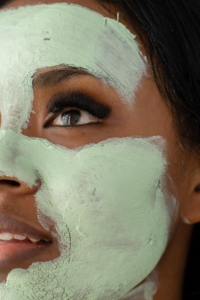 Primer plano de una mujer con una mascarilla verde natural en. la cara