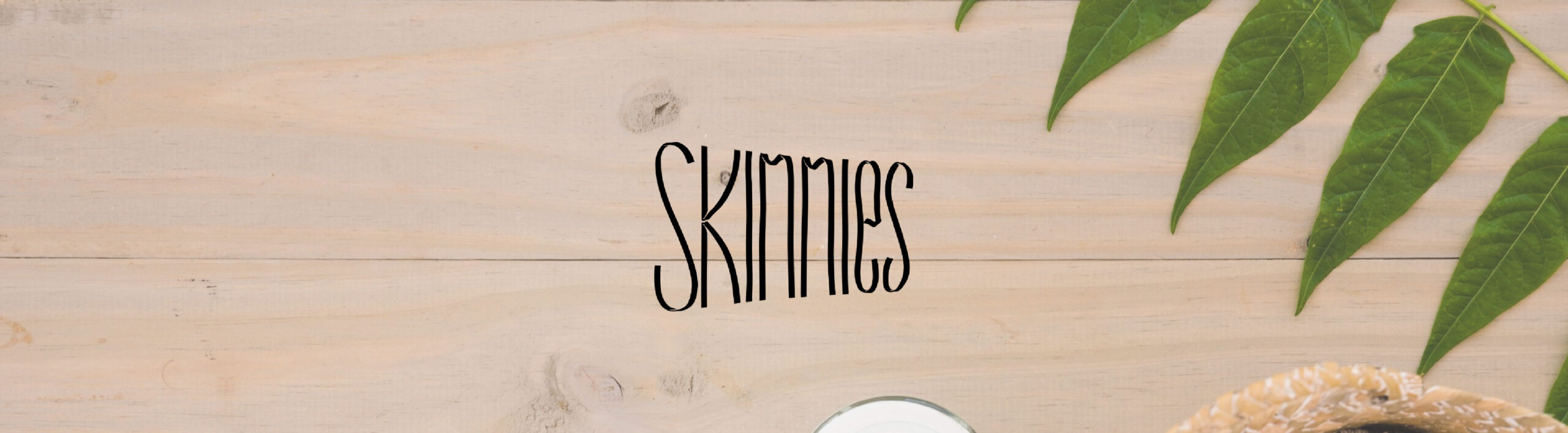 Banner promocional de la marca Skinnies con un fondo de madera natural y hojas verdes
